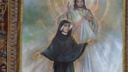 Sainte Faustine en habit religieux devant le tableau de la divine miséricorde représentant le Christ, un faisceau de lumière multicolore descend de son coeur